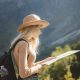 wanderlust-and-travel-concept-stylish-traveler-girl-in-hat-looking-at-map-exploring-woods--e1712714886988.jpg